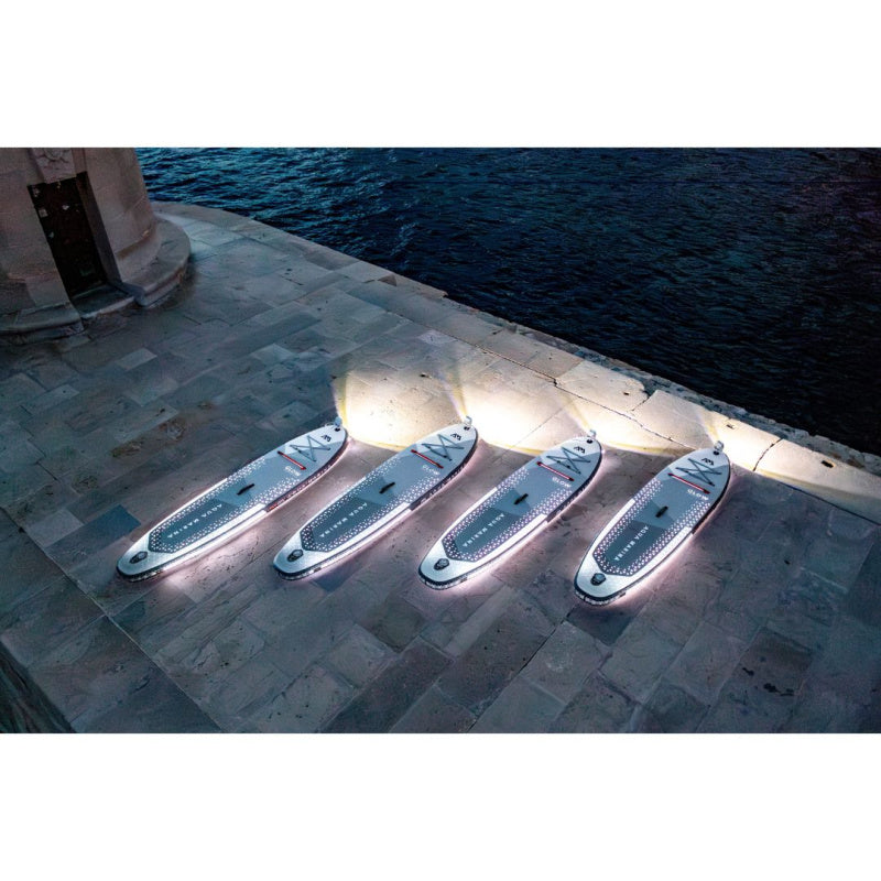 4 Aqua Marina Glow Inflatable SUPs Lit Up in White with Nose Lights On Lined Up on a Dock