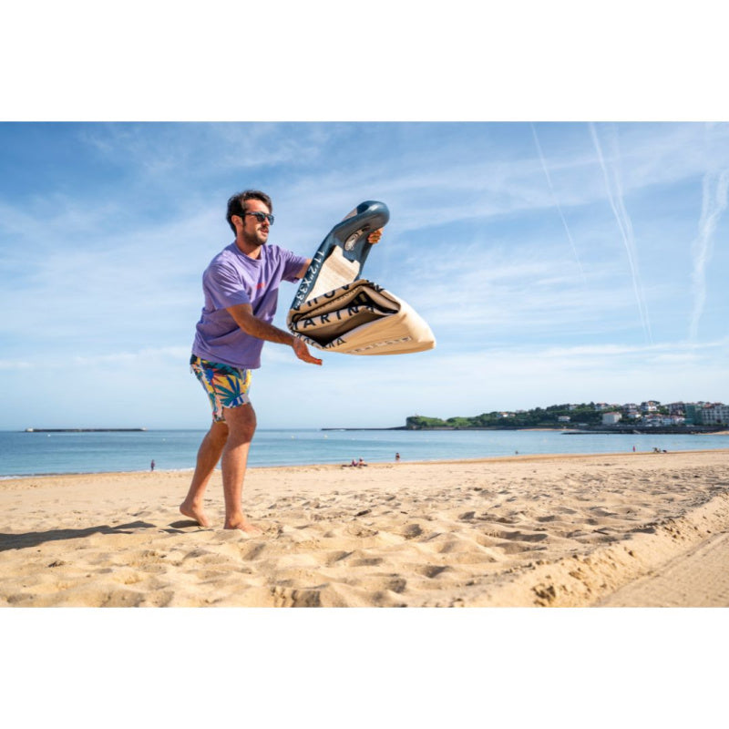 Man Unrolling Deflated Aqua Marina Magma SUP on Beach