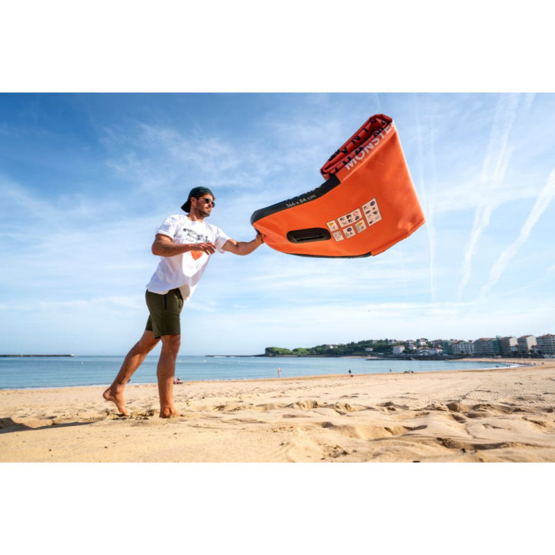 Man Unrolling Deflated Monster Inflatable SUP on the Beach