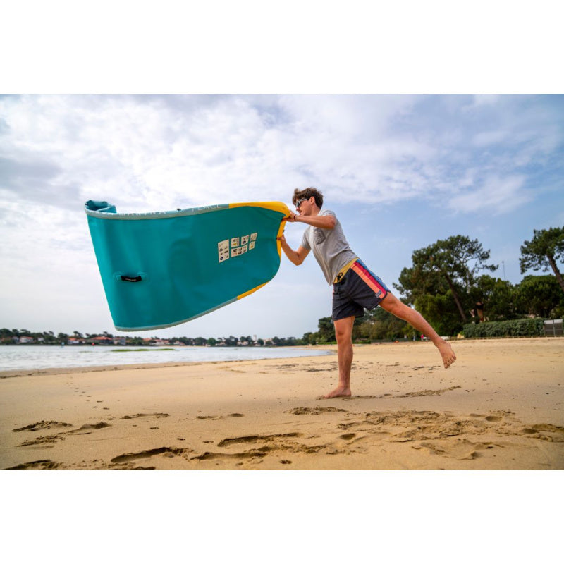 Man Unrolling Deflated Aqua Marina Peace Fitness Mat on Beach