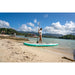 Woman Holding Paddle Walking into Ocean with Sipaboards Drive Tourer Electric SUP on Beach Next to Her