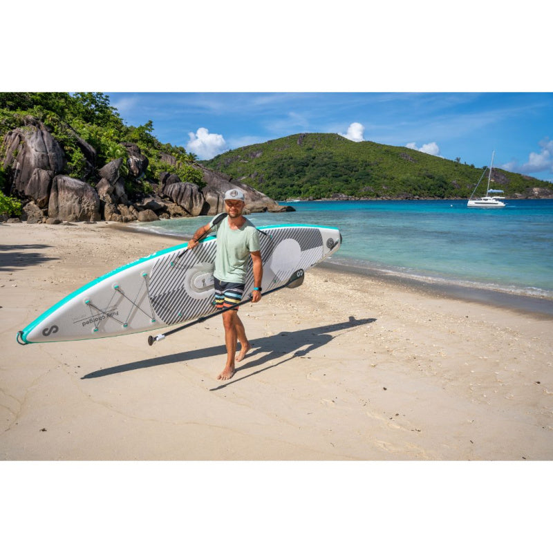 Man Using Shoulder Strap to Carry Sipaboards Drive Tourer Electric SUP on Beach While Holding the Paddle