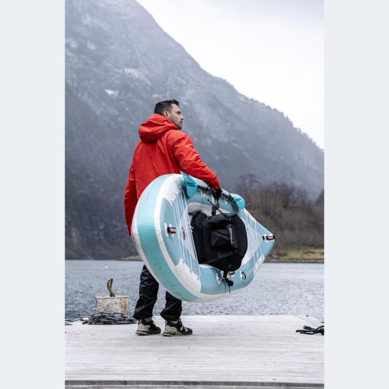 Man Carrying Spinera Adriatic 140 Inflatable Kayak on Dock with Mountains in the Back