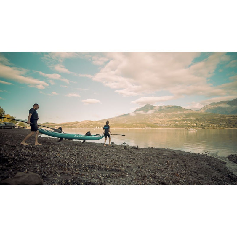 Man and Woman Carrying Spinera Hybris 410 Inflatable Kayak into Water with Mountains in the Background