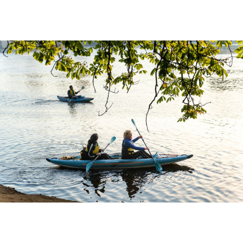 Two Women Paddling Spinera Tenaya 140 Inflatable Kayak Along the Shore and 1 Person Paddling in Background