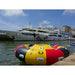 Spinera Professional Endless Ride 4-6 Person Towable Tube in Black, Yellow & Red in Water Along Dock with Superyachts in Back